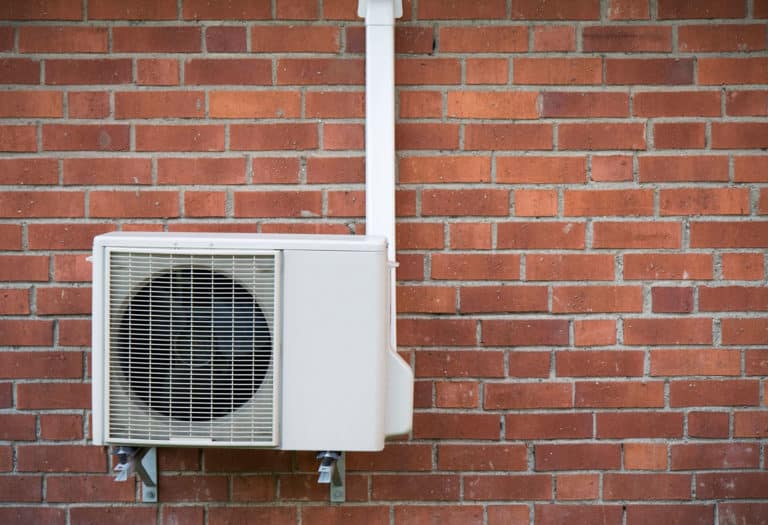 residential heat pump installed to an outside brick wall